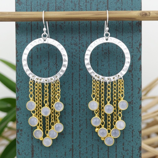 Серебряные серьги словно мятое серебро в форме полумесяца. Верхушка полумесяца крепится к застежке серьги.  От полумесяца идет три цепочки золотого цвета, у каждой на конце мелкий камушек лунный камень