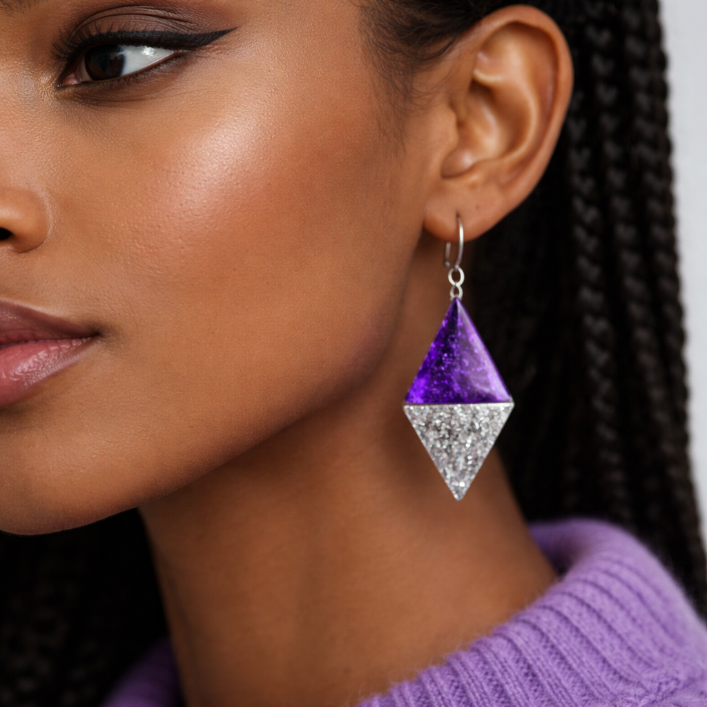 A picture that shows An Ethiopian woman’s half ear wearing purple sweater wearing Diomand shaped half purple and half glittery resin made with silver hooks earring