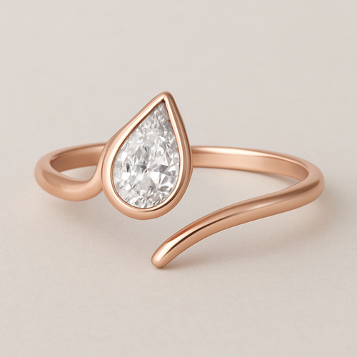 A delicate rose gold pinky ring featuring a 0.50-carat pear-shaped diamond set in a smooth bezel setting. The diamond is gently tilted to the left, creating a soft paisley-inspired curve that radiates feminine Yin energy — graceful, flowing, intuitive, and serene. The polished rose gold band enhances the gentle movement and balance of the design, symbolizing elegance, emotional depth, and the beauty of lunar energy.  