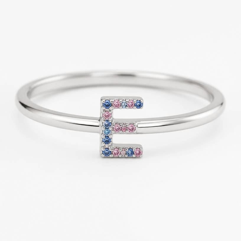 A minimalist women's ring, ultra-minimalist, very simple and clean, understated, no embellishments. um anel de 15 anos com inicial E com pedrinhas azul e pedrinhas rosa em volta
using the attached image as a visual reference, create A minimalist women's ring, ultra-minimalist, very simple and clean, understated, no embellishments. um anel de 15 anos com inicial E com pedrinhas azul e pedrinhas rosa em volta. photorealistic, just the design no text