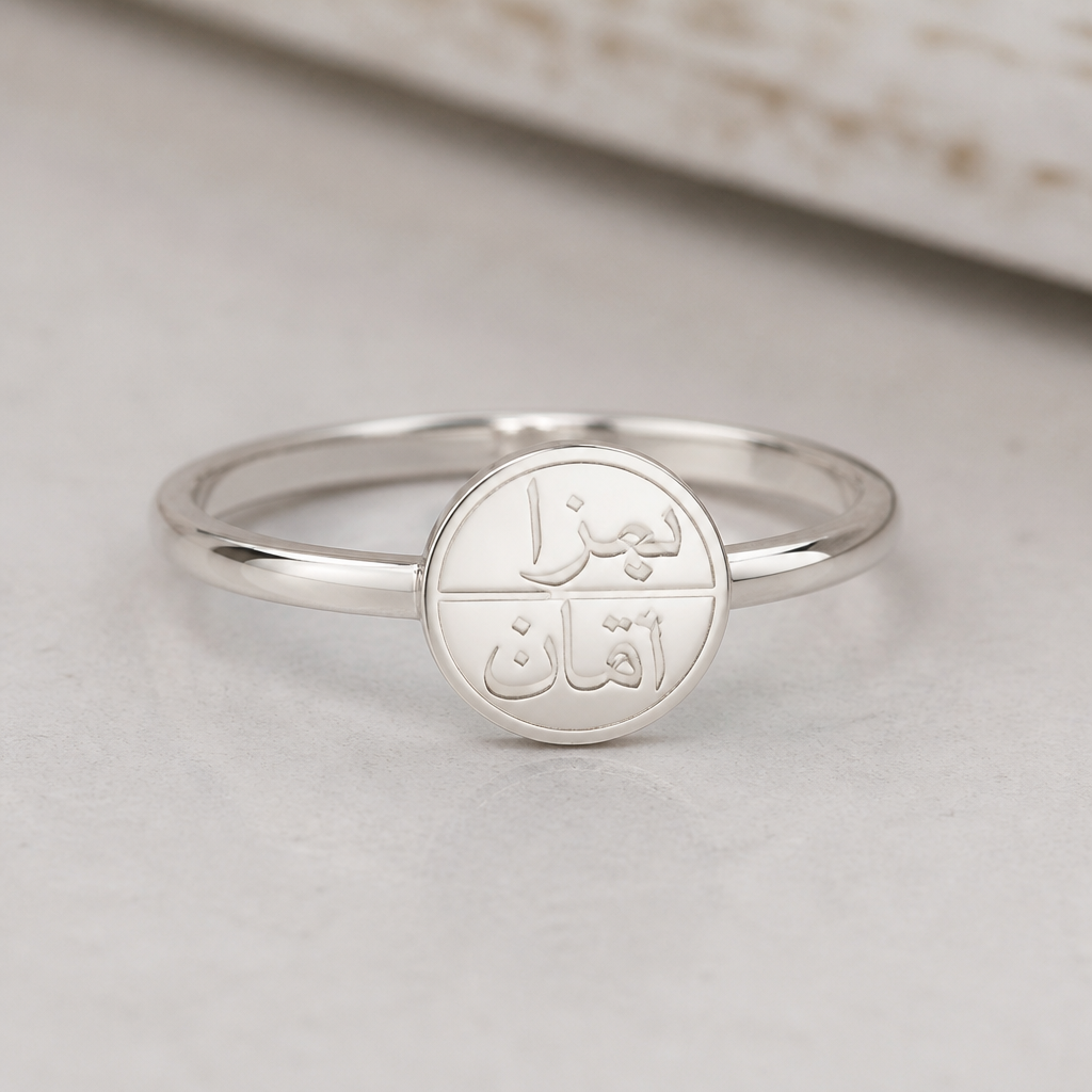 A women's ring made of silver suitable for daily wear. I want a simple, minimalist silver ring designed in a delicate, understated style. It should have the names 'Bara' and 'Obai' engraved in Arabic on it. I don't want it to be large or bulky, just elegant and refined I want the names please inside a circle
photorealistic jewelry design, A women's ring made of silver suitable for daily wear. I want a simple, minimalist silver ring designed in a delicate, understated style. It should have the names 'Bara' and 'Obai' engraved in Arabic on it. I don't want it to be large or bulky, just elegant and refined I want the names please inside a circle, modern style, just the design no text