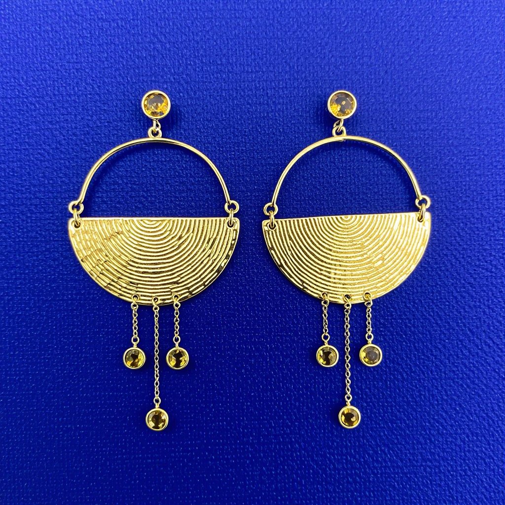 Золотые серьги словно мятое золото в форме узкого изящного полумесяца. Верхушка полумесяца крепится к застежке серьги.  От полумесяца идет три цепочки, у каждой на конце мелкий камушек цитрин
