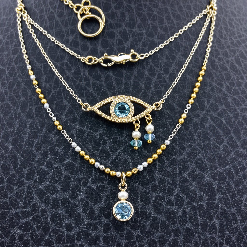 Тонкая цепочка с золотыми серебряными шариками и мелкими жемчужными камушками на цепочке есть кулон в форме глаза, зрачок глаза из аквамарина от глаза идет маленькая подвеска с маленькими камушками аквамарина 