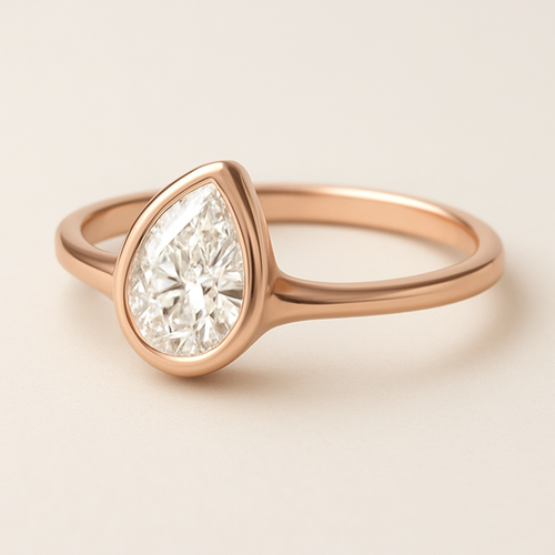 A modern and elegant rose gold ring featuring a 0.50-carat pear-shaped diamond set in a smooth bezel setting. The diamond is gently tilted to the left, forming a paisley-inspired silhouette that radiates feminine Yin energy — graceful, flowing, and intuitive. The polished rose gold band complements the organic curvature of the diamond, creating a refined balance between modern minimalism and soft, sensual elegance.