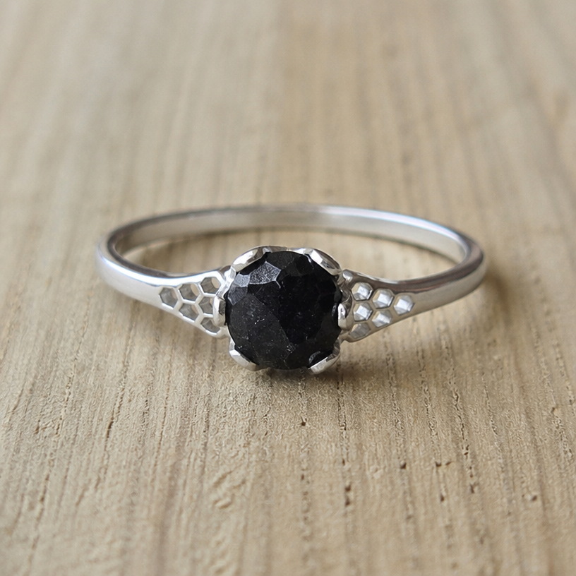 A women's ring made of silver, ultra-minimalist, very simple and clean, understated, no embellishments. take this black onyx and make some honeycomb outside the stone on either side
using the attached image as a visual reference, create A women's ring made of silver, ultra-minimalist, very simple and clean, understated, no embellishments. take this black onyx and make some honeycomb outside the stone on either side. photorealistic, just the design no text