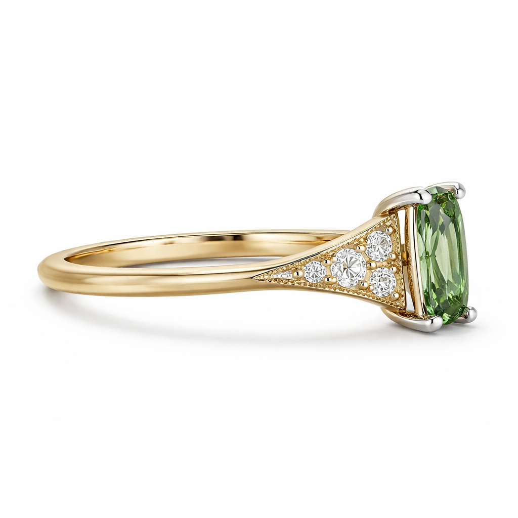 Side profile of A yellow gold 18 carat very thin band with a sharp angled edge ring. Central green sapphire in a n elongated cushion cut. Either side of the central sapphire are three very small diamonds on each side in a triangle formation with a bevelled edge border. The profile of the stones are raised higher with a bridge off the ring to accommodate a round wedding band underneath. All stones are held in place by four platinum pointy prongs.