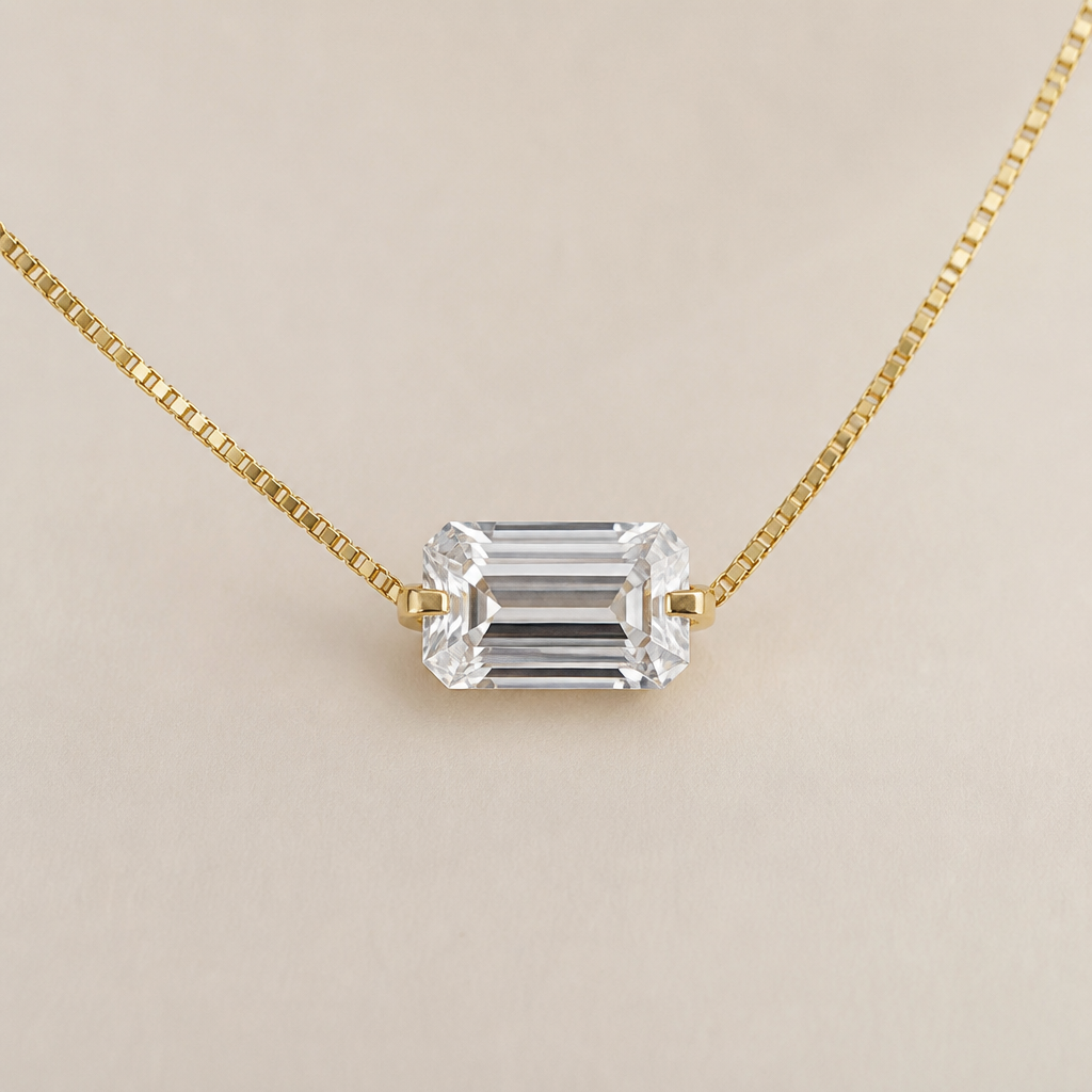 A 10ct clear emerald cut diamond with prongs. The diamond is east west on a thin box chain. All of the metal is yellow gold. The prongs connect to the pendant in the middle of the diamond, not the top corners
photorealistic jewelry design, A 10ct clear emerald cut diamond with prongs. The diamond is east west on a thin box chain. All of the metal is yellow gold. The prongs connect to the pendant in the middle of the diamond, not the top corners , minimalist style, just the design no text