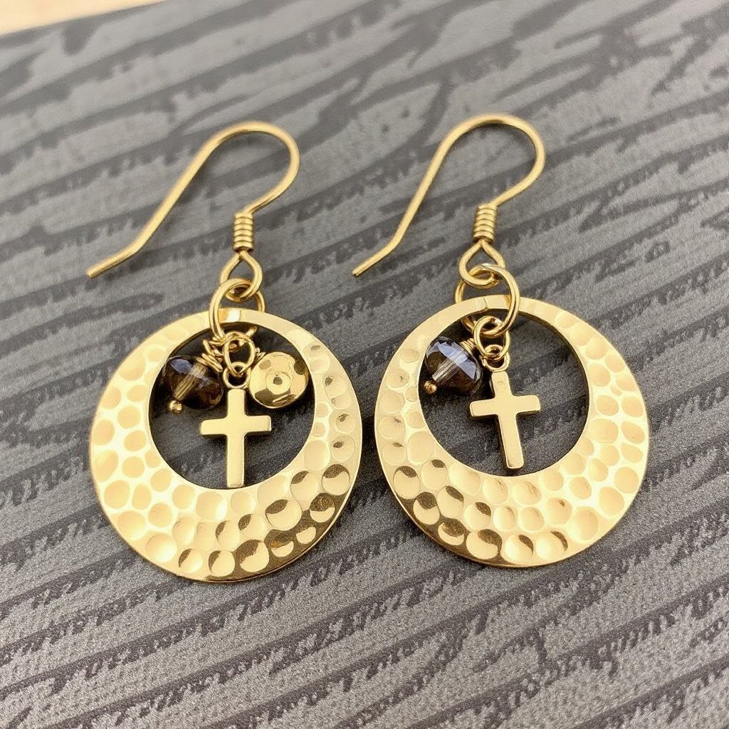 Золотые серьги словно мятое золото в форме узкого изящного полумесяца. Верхушка полумесяца крепится к застежке серьги. К нижней части полумесяца крепятся три подвески: миниатюрный золотой египетриский крест, очень маленький кристалл раухтопаза и маленький золотой кружочек с мятым эффектом плоский