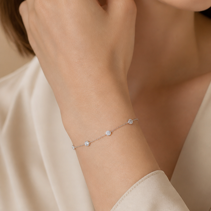 Jewelry photoshoot (worn)
Show the jewelry piece from the image worn by an elegant model in a professional editorial photograph, soft studio lighting. Reproduce the jewelry's exact design, metal, stones and details faithfully. Photorealistic, no text. Additional instructions: "Close-up beauty/editorial photo of a woman's wrist and hand, fair light skin tone, gently relaxed pose (resting on a soft surface or lightly touching her face/collarbone). Soft, warm neutral studio background (beige/cream tones), softly blurred, shallow depth of field.
She wears a delicate sterling silver chain bracelet featuring a small round bezel-set cubic zirconia stone on one side of the chain and a small sideways cross charm on the other side, connected by a fine cable chain.
METAL FINISH: the sterling silver must be rhodium-plated — bright, cool-white, and reflective with a polished mirror-like shine, not dull or matte. The metal should catch light naturally and sparkle realistically, without looking overly glossy, plastic, or artificially glowing.
SKIN REALISM REQUIREMENT: skin must look completely natural and photorealistic — fair, light skin tone to enhance the contrast and shine of the silver, with visible fine skin texture, natural pores, subtle imperfections. Avoid any smooth, plastic, airbrushed, CGI, or overly retouched look. Lighting soft and warm, casting natural gentle shadows.
STRICT SIZE REQUIREMENT: the bracelet must stay true to real-life scale, fine and delicate — the round stone approximately 0.6cm, the cross charm small and slim, both proportionate to the wrist. Do not enlarge or oversize.
BRACELET POSITION: the chain drapes naturally around the wrist, with the round stone and cross charm both visible and facing forward, sitting flat against the skin.
Close-up beauty/editorial photo of a woman's wrist and hand, fair light skin tone, gently relaxed pose (resting on a soft surface or lightly touching her face/collarbone). Soft, warm neutral studio background (beige/cream tones), softly blurred, shallow depth of field.
She wears a delicate sterling silver double-chain bracelet featuring a small infinity symbol charm, partially lined with sparkling pavé cubic zirconia stones on one side, connected by two fine parallel cable chains.
METAL FINISH: the sterling silver must be rhodium-plated — bright, cool-white, and reflective with a polished mirror-like shine, not dull or matte. The metal should catch light naturally and sparkle realistically, without looking overly glossy, plastic, or artificially glowing.
SKIN REALISM REQUIREMENT: skin must look completely natural and photorealistic — fair, light skin tone to enhance the contrast and shine of the silver, with visible fine skin texture, natural pores, subtle imperfections. Avoid any smooth, plastic, airbrushed, CGI, or overly retouched look. Lighting soft and warm, casting natural gentle shadows.
STRICT SIZE REQUIREMENT: the bracelet must stay true to real-life scale, fine and delicate — the infinity charm small and slim, proportionate to the wrist, double chain thin and dainty. Do not enlarge or oversize.
BRACELET POSITION: the double chain drapes naturally around the wrist, with the infinity charm centered and facing forward, sitting flat against the skin.
"Close-up beauty/editorial photo of a woman's wrist and hand, fair light skin tone, gently relaxed pose (resting on a soft surface or lightly touching her face/collarbone). Soft, warm neutral studio background (beige/cream tones), softly blurred, shallow depth of field.
She wears a delicate sterling silver chain bracelet featuring four small round bezel-set cubic zirconia stones evenly spaced along a fine cable chain.
METAL FINISH: the sterling silver must be rhodium-plated — bright, cool-white, and reflective with a polished mirror-like shine, not dull or matte. The metal should catch light naturally and sparkle realistically, without looking overly glossy, plastic, or artificially glowing.
SKIN REALISM REQUIREMENT: skin must look completely natural and photorealistic — fair, light skin tone to enhance the contrast and shine of the silver, with visible fine skin texture, natural pores, subtle imperfections. Avoid any smooth, plastic, airbrushed, CGI, or overly retouched look. Lighting soft and warm, casting natural gentle shadows.
STRICT SIZE REQUIREMENT: the bracelet must stay true to real-life scale, fine and delicate — each round stone approximately 0.5cm, evenly spaced along the thin chain, proportionate to the wrist. Do not enlarge or oversize.
BRACELET POSITION: the chain drapes naturally around the wrist, with all four stones visible and evenly spaced, sitting flat against the skin, catching soft light.
Mood: elegant, minimal, intimate — high-end jewelry brand photography style, sharp focus on the bracelet while keeping the composition natural and soft.".