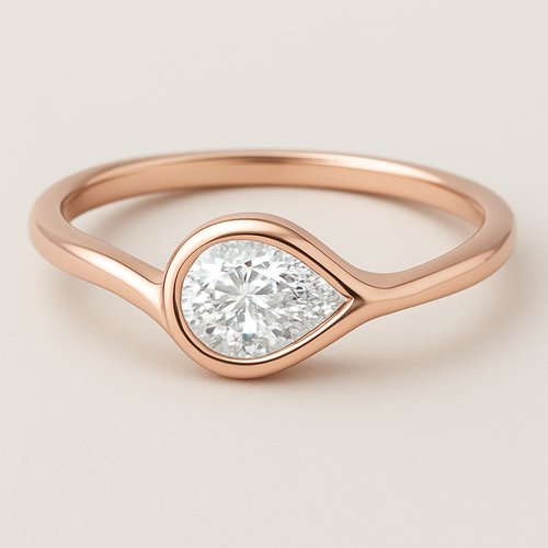 A delicate rose gold pinky ring featuring a 0.50-carat pear-shaped diamond set in a smooth bezel setting. The diamond is gently tilted to the left, creating a soft paisley-inspired curve that radiates feminine Yin energy — graceful, flowing, intuitive, and serene. The polished rose gold band enhances the gentle movement and balance of the design, symbolizing elegance, emotional depth, and the beauty of lunar energy.  
