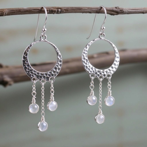 Серебряные серьги словно мятое сер ебро в форме полумесяца. Верхушка полумесяца крепится к застежке серьги.  От полумесяца идет три цепочки, у каждой на конце мелкий камушек лунный камень