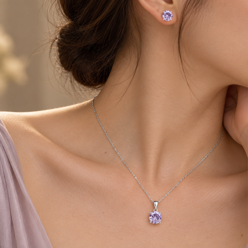 Jewelry photoshoot (worn)
Show the jewelry piece from the image worn by an elegant model in a professional editorial photograph, soft studio lighting. Reproduce the jewelry's exact design, metal, stones and details faithfully. Photorealistic, no text. Additional instructions: "Close-up editorial jewelry photo of a woman's neck, collarbone, ear, and upper chest, cropped so the face is fully out of frame. She wears soft, elegant clothing, only a small part of the fabric visible at the edge of the frame.
VARY THE POSE: do not repeat the same head tilt, shoulder position, or framing as previous generations. Use natural variations such as: head turned left or right, chin slightly up or down, one shoulder raised or relaxed, hair swept to either side or tucked back, camera angle shifted slightly higher or lower. Keep the framing tight on the neck, collarbone, and ear (face always out of frame), but make the pose feel distinct and natural.
She wears a sterling silver necklace with a round, multi-faceted purple/lavender cubic zirconia pendant (cut with a spiral, rose-flower faceted pattern) set in a four-prong setting, and a matching pair of round faceted purple cubic zirconia stud earrings with the same spiral rose-cut faceting.
METAL FINISH: the sterling silver must be rhodium-plated — bright, cool-white, and reflective with a polished mirror-like shine, not dull or matte. The metal should catch light naturally, without looking overly glossy, plastic, or artificially glowing.
STONE COLOR AND DETAIL: the cubic zirconia stones must be a soft lavender-purple color, sparkling and perfectly faceted with a distinctive spiral rose-cut pattern, catching light realistically with natural brilliance and multiple light reflections.
STRICT SIZE REQUIREMENT: the pendant (including bail) must be exactly 2cm height x 0.8cm width, and the earrings exactly 0.6cm each, true to real-life scale against the neck, collarbone, and ear. Do not enlarge or oversize — the pendant should look delicate on the chest, not bulky or overly large.
SKIN REALISM REQUIREMENT: skin must look completely natural and photorealistic — visible fine skin texture, natural pores, subtle imperfections, soft even tone. Avoid any smooth, plastic, airbrushed, CGI, or overly retouched look. Lighting soft and warm, casting natural gentle shadows.
CHAIN AND PENDANT POSITION: fine cable chain draping naturally in a soft V-shape along the collarbone, with the round pendant hanging centered at the lowest point of the chain, attached by a teardrop-shaped bail. The stud earrings sit naturally and securely on the earlobes, fully visible and in focus.
Background softly blurred, warm and neutral, shallow depth of field. Mood: elegant, minimal, intimate — natural high-end jewelry brand photography style, face not shown, jewelry clearly and accurately rendered in true color and correct scale..