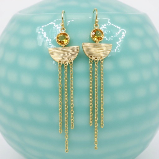Золотые серьги словно мятое золото в форме узкого изящного полумесяца. Верхушка полумесяца крепится к застежке серьги.  От полумесяца идет три цепочки, у каждой на конце мелкий камушек цитрин