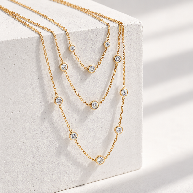 Jewelry photoshoot (worn)
Show the jewelry piece from the image worn by an elegant model in a professional editorial photograph, soft studio lighting. Reproduce the jewelry's exact design, metal, stones and details faithfully. Photorealistic, no text. Additional instructions: "Photorealistic product photography, several delicate gold necklaces draped diagonally over the edge of a white geometric concrete block, cascading down at an angle, pendants hanging freely below the block's edge at varying lengths. Soft natural daylight from the side, creating soft directional shadows on the white surface. Clean minimalist white background, high-end jewelry catalog aesthetic, sharp focus throughout, warm gold tones, 8k resolution, no text, no logo, no model, no hands.".