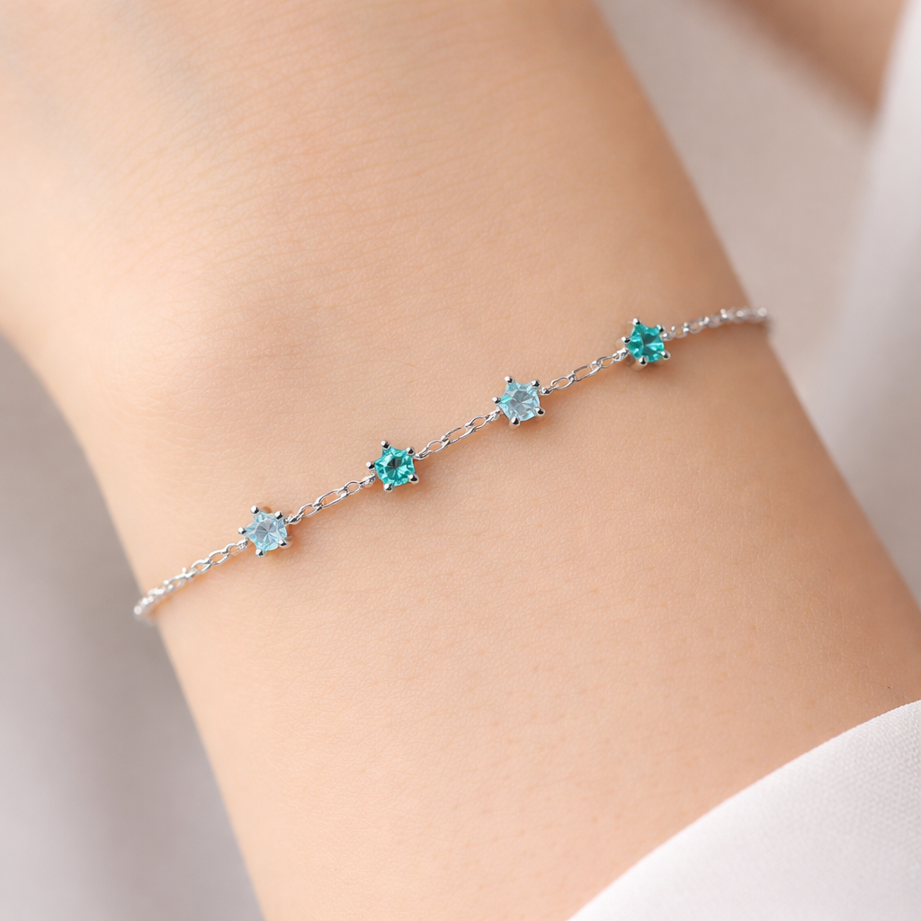 A minimalist women's bracelet made of silver with aquamarine and turquoise stones suitable for daily wear. pulseira com varias pequenas estrelas azuis