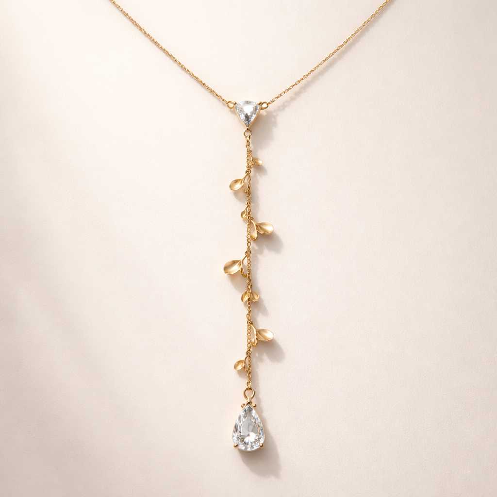 Elegant Y-shaped gold necklace design. A delicate fine gold chain with a small pear-cut diamond at the center connection point. From the diamond, a thin vertical chain drops down, decorated with multiple small gold flower petals instead of a plain chain. Each petal is minimal, organic, and softly curved, placed asymmetrically along the dangling chain, creating a feminine and luxurious look. At the end of the chain, a single pear-cut diamond pendant. High-end jewelry design, minimal luxury style, 18k gold, realistic lighting, studio background, ultra-detailed, refined craftsmanship.