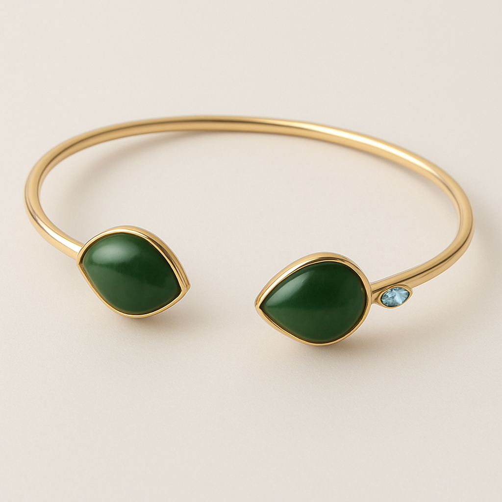 Create a yellow gold cuff with two pear shaped pieces of nephrite jade at the ends and two petite pear shaped blue topaz’s set in the gold of the bracelet