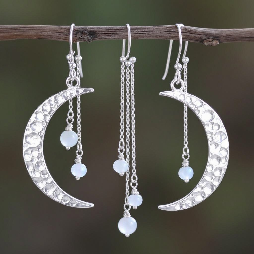 Серебряные серьги словно мятое сер ебро в форме полумесяца. Верхушка полумесяца крепится к застежке серьги.  От полумесяца идет три цепочки, у каждой на конце мелкий камушек лунный камень