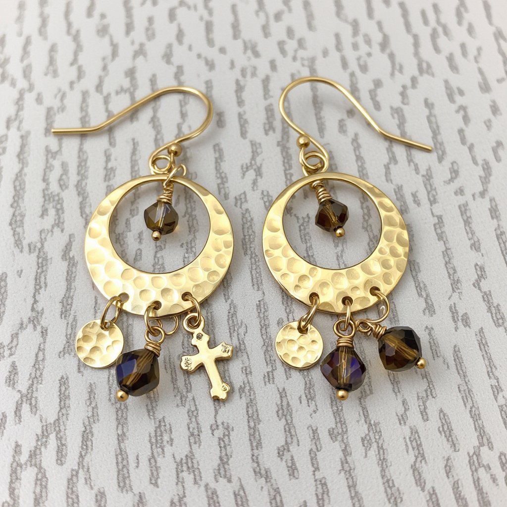 Золотые серьги словно мятое золото в форме узкого изящного полумесяца. Верхушка полумесяца крепится к застежке серьги. К нижней части полумесяца крепятся три подвески: миниатюрный золотой египетриский крест, очень маленький кристалл раухтопаза и маленький золотой кружочек с мятым эффектом плоский