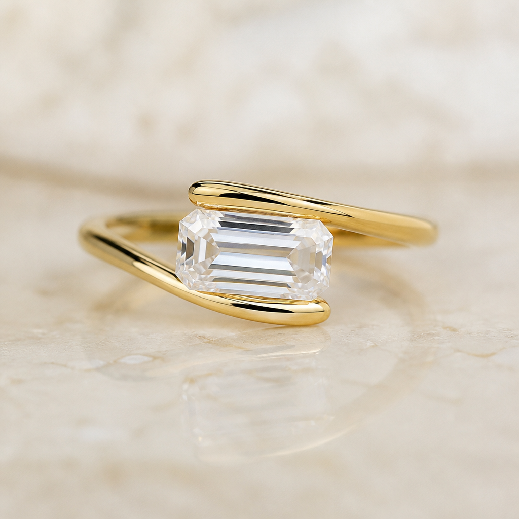 "Emerald cut diamond with gold bypass ring wrapping around the top and bottom of diamond. Diamond is east west. Metal is yellow gold
photorealistic jewelry design, "Emerald cut diamond with gold bypass ring wrapping around the top and bottom of diamond. Diamond is east west. Metal is yellow gold , minimalist style, just the design no text