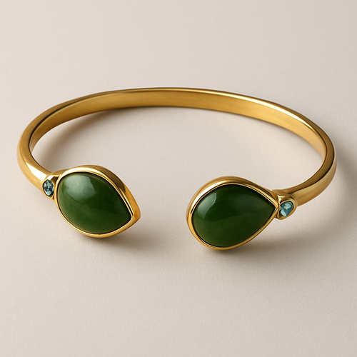 Create a yellow gold cuff with two pear shaped pieces of nephrite jade at the ends and two petite pear shaped blue topaz’s set in the gold of the bracelet