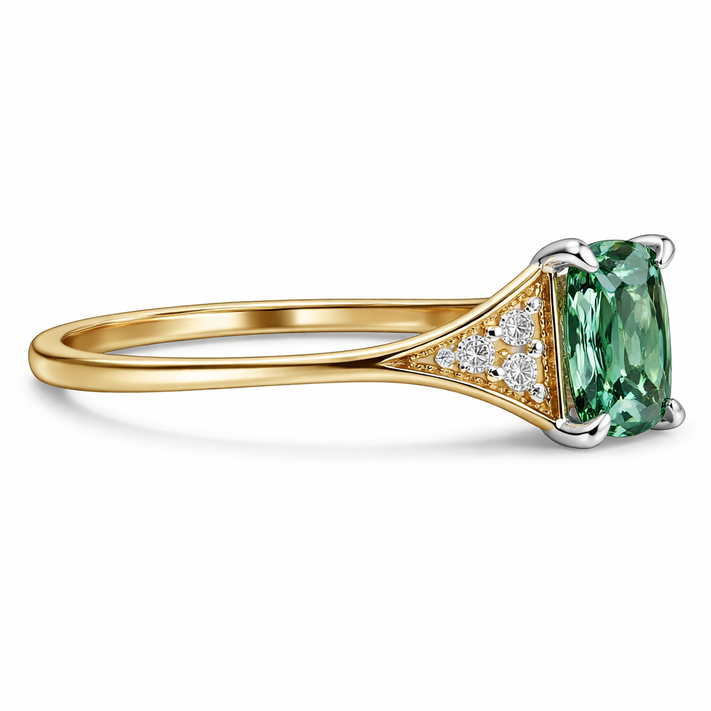 Side profile of A yellow gold 18 carat very thin band with a sharp angled edge ring. Central green sapphire in a n elongated cushion cut. Either side of the central sapphire are three very small diamonds on each side in a triangle formation with a bevelled edge border. The profile of the stones are raised higher with a bridge off the ring to accommodate a round wedding band underneath. All stones are held in place by four platinum pointy prongs.
