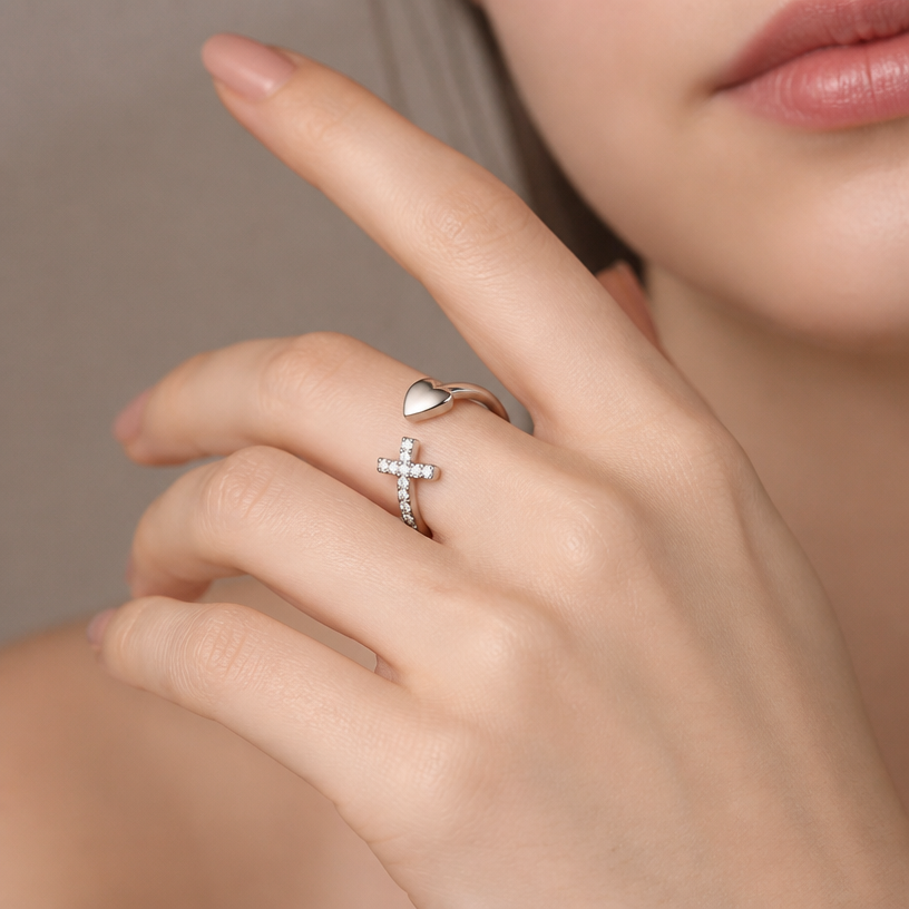 Jewelry photoshoot (worn)
Show the jewelry piece from the image worn by an elegant model in a professional editorial photograph, soft studio lighting. Reproduce the jewelry's exact design, metal, stones and details faithfully. Photorealistic, no text. Additional instructions: Detailed macro photography of the specific open-loop 925 sterling silver ring from reference images, featuring the smooth polished heart on one side and the sparkling cubic zirconia pave cross on the other. The ring is worn on the delicate, fair-skinned index finger of a female model. Soft, studio lighting highlighting the metal and the sparkle of the stones. Blurred, minimalist neutral background. 4k, high resolution, photorealistic..