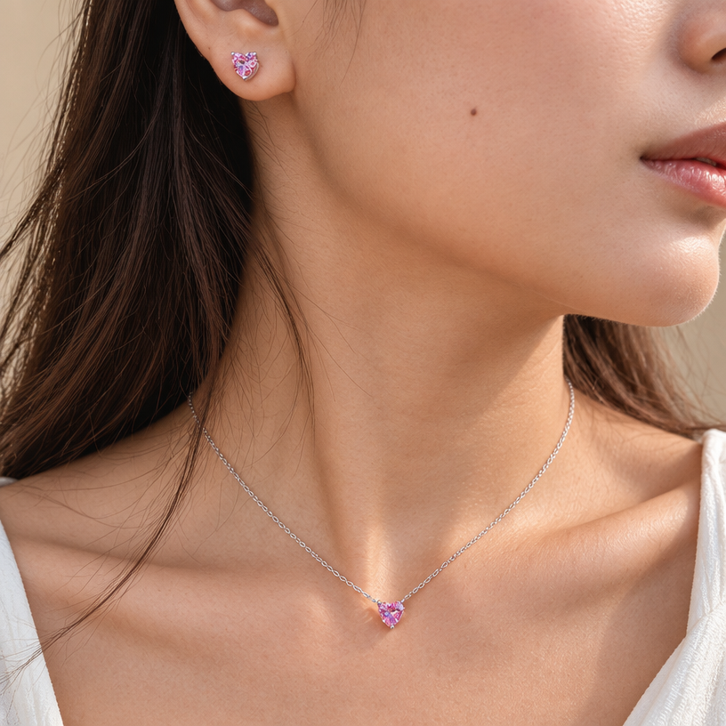 Jewelry photoshoot (worn)
Show the jewelry piece from the image worn by an elegant model in a professional editorial photograph, soft studio lighting. Reproduce the jewelry's exact design, metal, stones and details faithfully. Photorealistic, no text. Additional instructions: "Close-up editorial jewelry photo of a woman's neck, collarbone, and ear, tightly cropped (chin, jaw, and lips partially in frame, head gently turned to the side). She wears a sterling silver necklace with a heart-shaped pink cubic zirconia pendant set in a simple four-prong setting, and a matching heart-shaped pink cubic zirconia stud earring.
METAL FINISH: the sterling silver must be rhodium-plated — bright, cool-white, and reflective with a polished mirror-like shine, not dull or matte. The metal should catch light naturally, without looking overly glossy, plastic, or artificially glowing.
STONE DETAIL: the pink heart-cut cubic zirconia stones must be vivid pink, sparkling, and perfectly faceted with a clean heart shape, catching light realistically with natural sparkle and brilliance — not flat or dull.
SKIN REALISM REQUIREMENT: skin must look completely natural and photorealistic — visible fine skin texture, natural pores, subtle imperfections, soft even tone. Avoid any smooth, plastic, airbrushed, CGI, or overly retouched look. Lighting soft and warm, casting natural gentle shadows.
STRICT SIZE REQUIREMENT: the pendant must be exactly 0.7cm height, and the earring exactly 0.6cm height, true to real-life scale against the neck and ear — do not enlarge or oversize.
CHAIN AND PENDANT POSITION: fine cable chain draping naturally in a soft V-shape along the collarbone, with the heart pendant hanging centered at the lowest point of the chain, point of the heart facing down, attached by a small prong setting at the top.
Background a warm blurred neutral tone (cream/beige), shallow depth of field. Mood: elegant, minimal, intimate — natural high-end jewelry brand photography style, matching the reference close-up shot.
FORMAT: generate this image in Instagram Post format, square aspect ratio 1:1 (1080x1080px), with the jewelry and face composition centered and balanced within the frame..